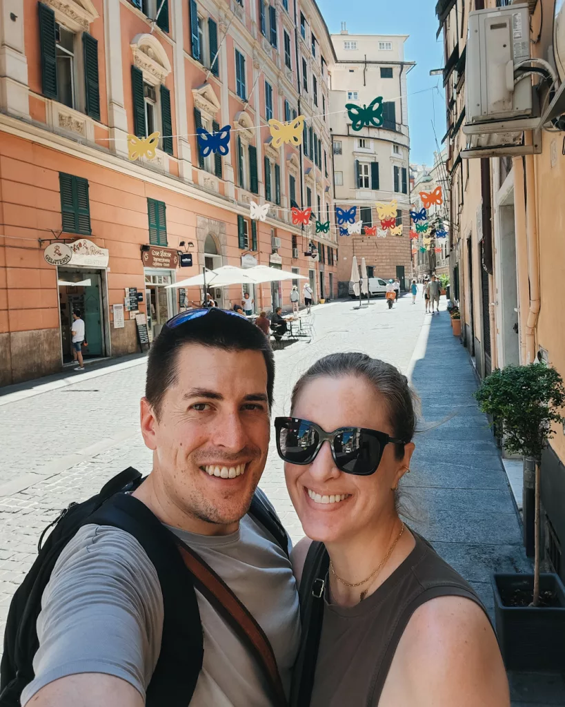 Selfie of me and my spouse, with a street in Genoa, Italy behind us
